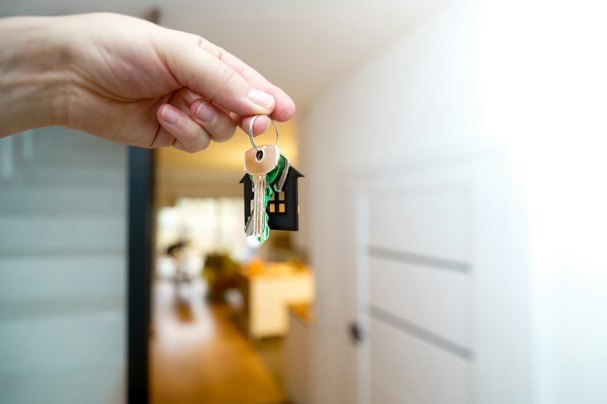 A hand holding house keys in the doorway of a home